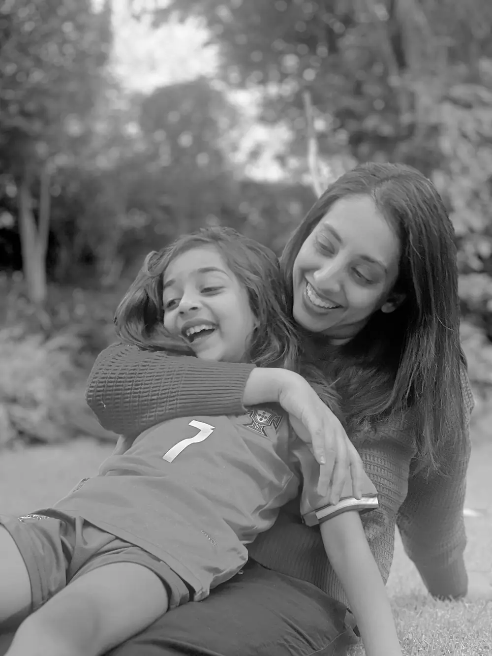 Dr Nazrana Vally laughing in the garden with her child — mother of three and founder of Bright Smiles - Savoy Dental Centre